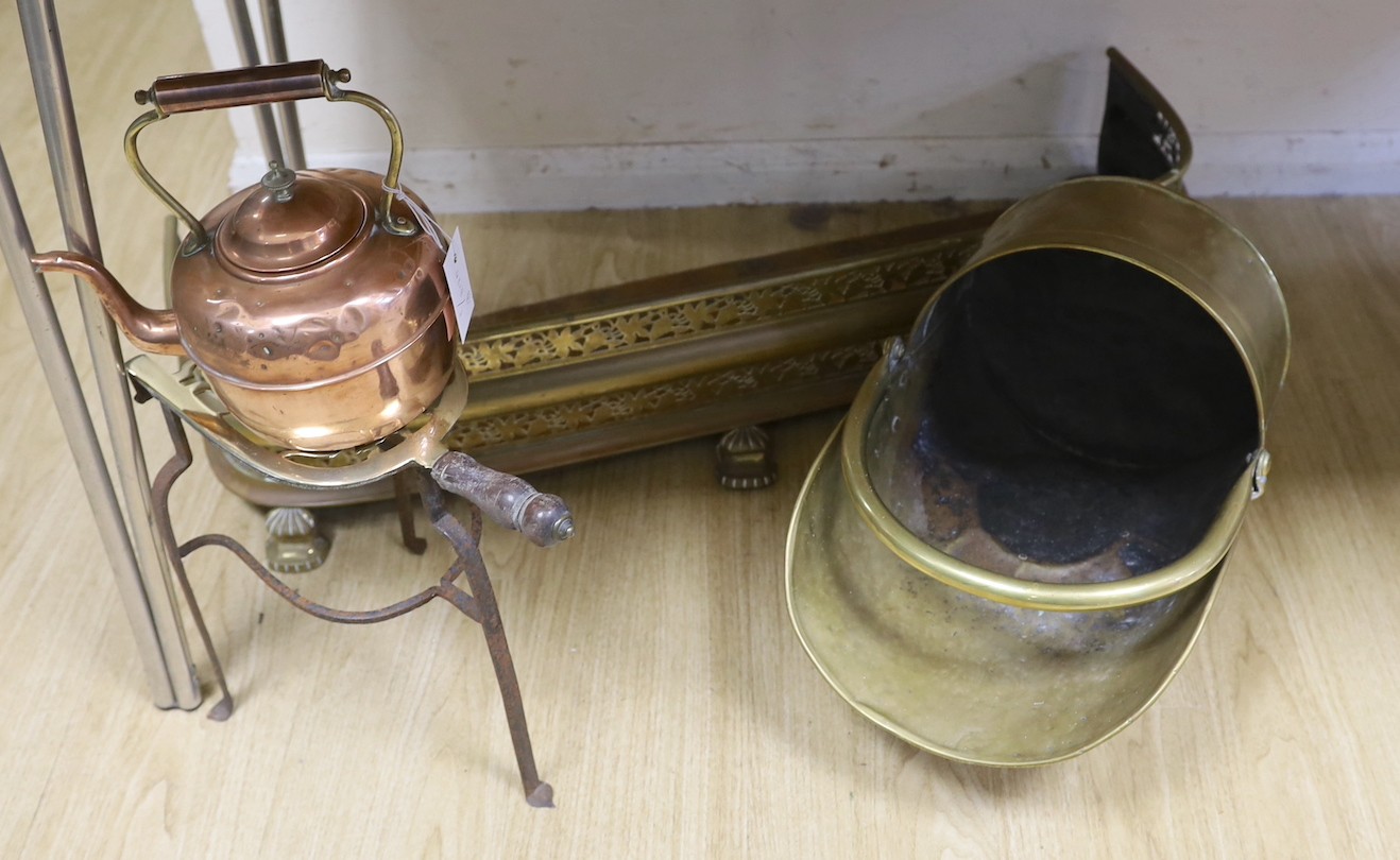 A copper kettle and trivet stand, a brass coal scuttle and a fender, Trivet 33 cms high.